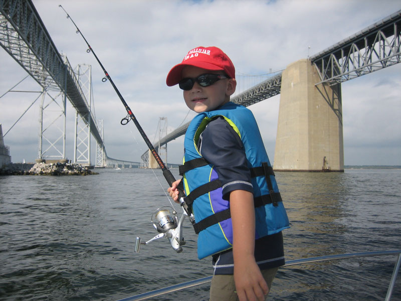 boy fishing on a boat under the bay bridge