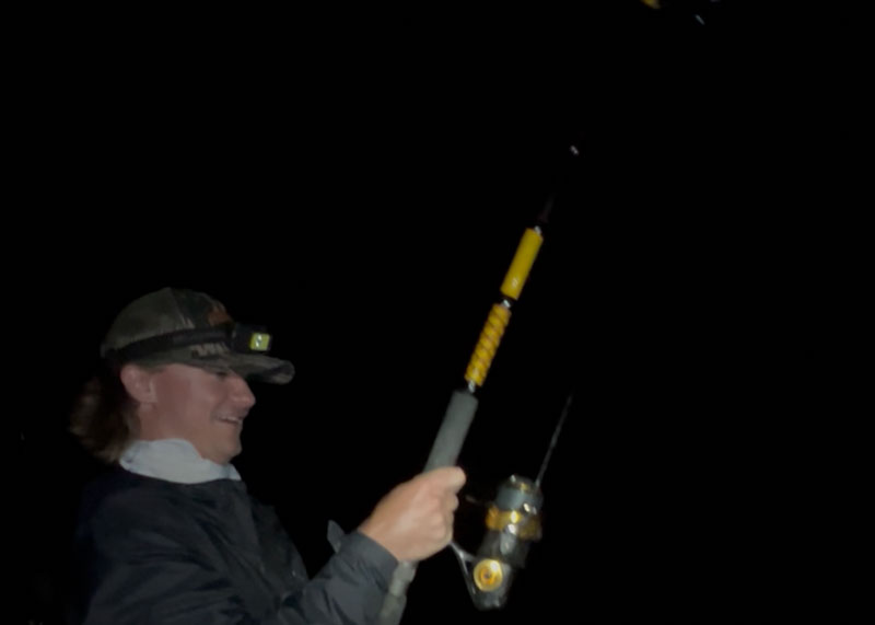 angler fishing from shore for bull redfish at night